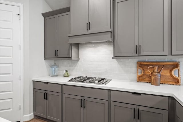 171 William Clayton Dr, Buda, TX 78610 - kitchen with gray cabinets, stainless steel gas cooktop, decorative backsplash, under cabinet range hood, and light countertops