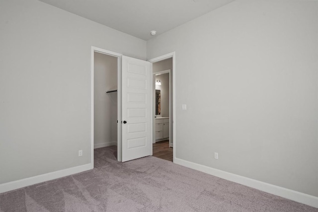 unfurnished bedroom with carpet floors, baseboards, and a walk in closet