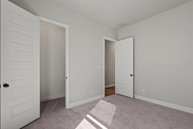 unfurnished bedroom with baseboards, carpet flooring, and visible vents