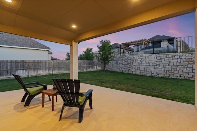 patio terrace at dusk featuring a yard and a fenced backyard