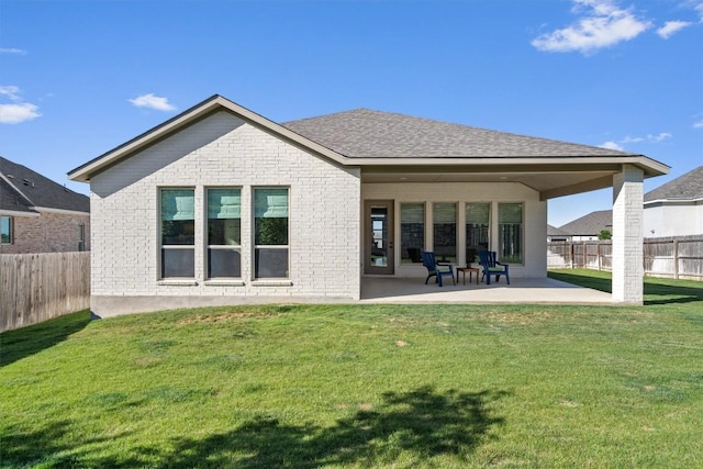 back of property featuring a fenced backyard, a patio, a yard, and brick siding