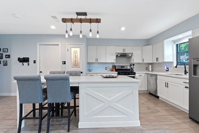 713 Buckingham Pl, Austin, TX 78745 - kitchen featuring visible vents, a sink, light countertops, under cabinet range hood, and stainless steel appliances