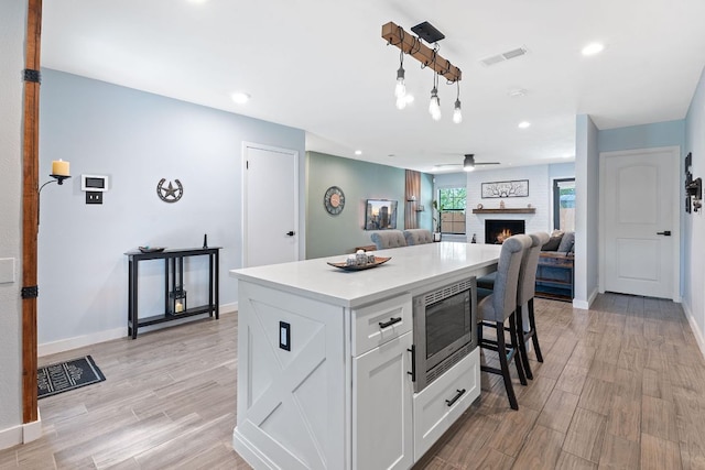 713 Buckingham Pl, Austin, TX 78745 - kitchen with a fireplace, white cabinetry, stainless steel microwave, a kitchen island, and visible vents