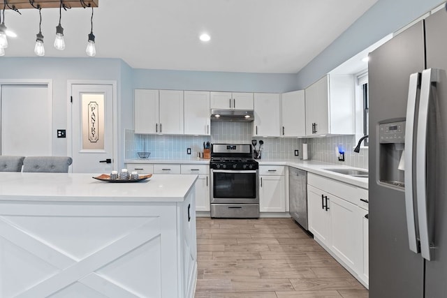 713 Buckingham Pl, Austin, TX 78745 - kitchen with light wood-type flooring, light countertops, under cabinet range hood, a sink, and stainless steel appliances