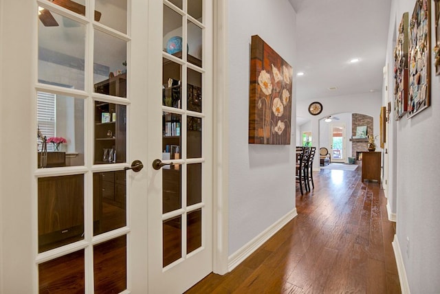 hall featuring french doors, arched walkways, baseboards, wood-type flooring, and recessed lighting