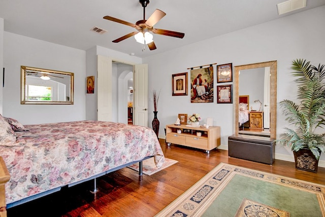 bedroom with visible vents, arched walkways, baseboards, and wood finished floors