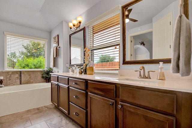 bathroom with double vanity, ceiling fan, a bath, a sink, and lofted ceiling