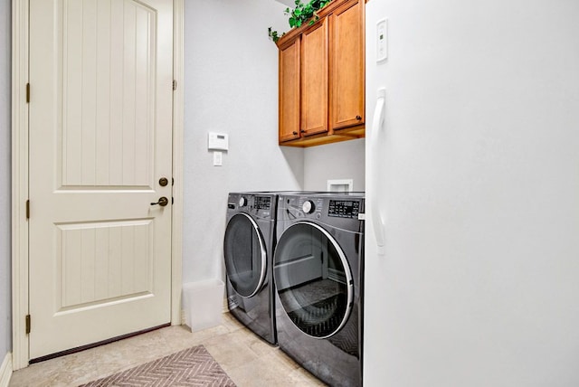washroom with cabinet space, separate washer and dryer, and light tile patterned floors