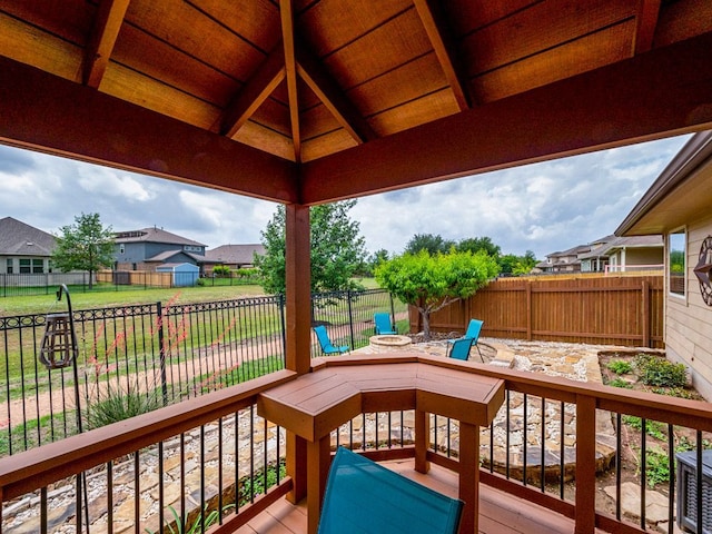 wooden terrace featuring a fenced backyard, a gazebo, an outdoor fire pit, a yard, and a residential view