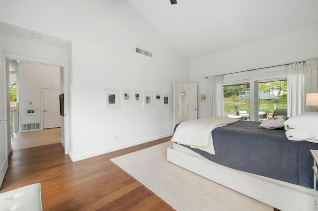 bedroom with baseboards, high vaulted ceiling, visible vents, and wood finished floors