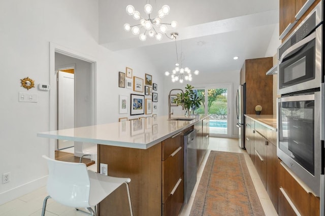 419 Sunfish St, Lakeway, TX 78734 - kitchen featuring a chandelier, brown cabinetry, a large island, modern cabinets, and appliances with stainless steel finishes