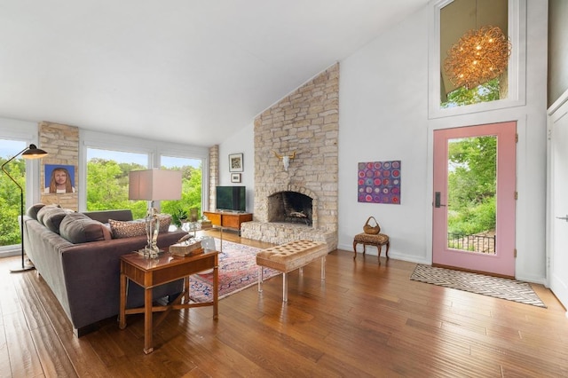 living room featuring a healthy amount of sunlight, high vaulted ceiling, a fireplace, and wood finished floors