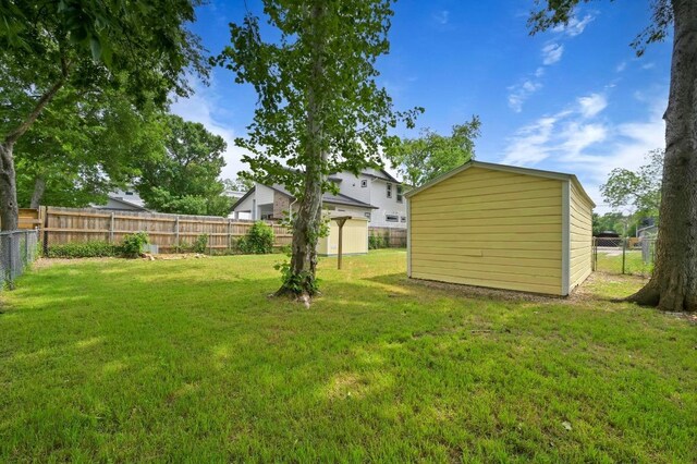 view of yard with a fenced backyard, a storage unit, and an outbuilding