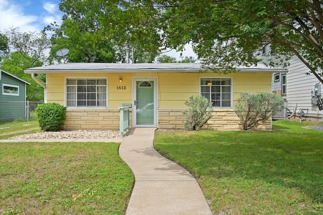 view of front of property featuring fence, a front yard, and stone siding