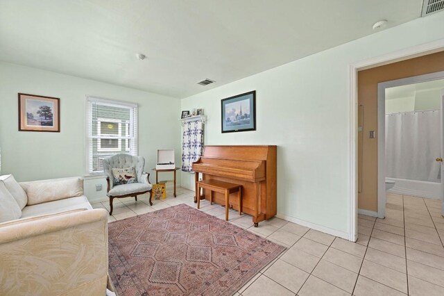 living area featuring baseboards, light tile patterned flooring, and visible vents