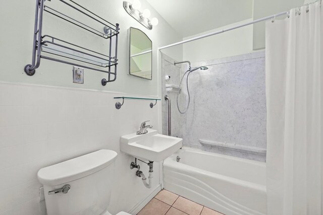 bathroom featuring shower / bath combo, toilet, tile patterned floors, a wainscoted wall, and tile walls