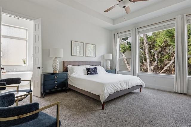 bedroom featuring carpet floors, a tray ceiling, ceiling fan, and connected bathroom