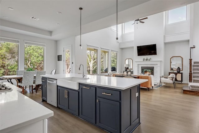 kitchen featuring a ceiling fan, visible vents, wood finished floors, a sink, and light countertops