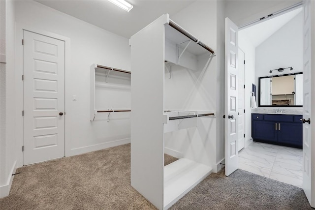 spacious closet with a sink, light colored carpet, and marble finish floor