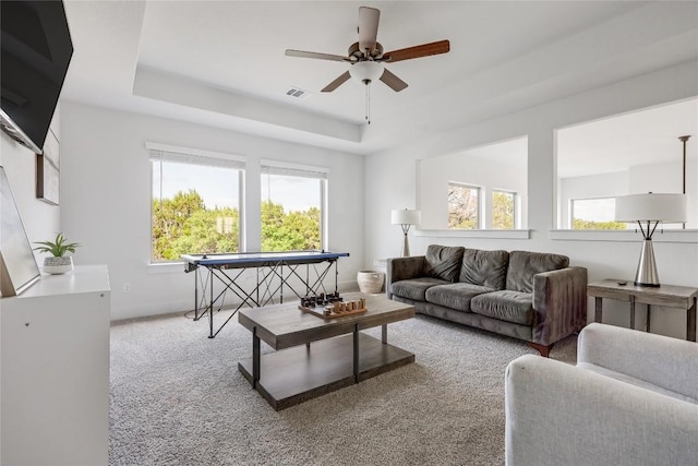 living room with visible vents, a ceiling fan, a raised ceiling, and carpet floors