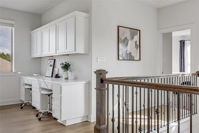 office area featuring light wood-style floors, baseboards, and built in desk