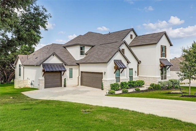 modern inspired farmhouse featuring driveway, a front yard, an attached garage, stone siding, and stucco siding