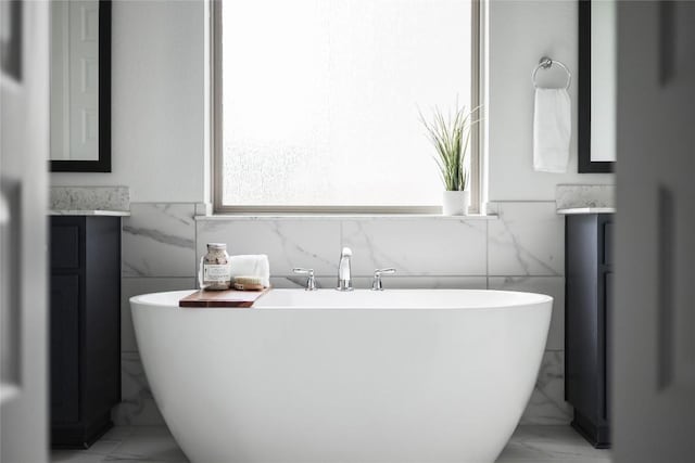 bathroom featuring a freestanding tub, tile walls, marble finish floor, and vanity