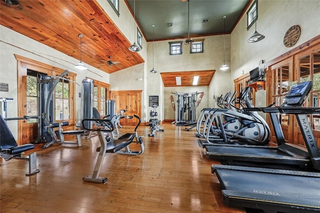 gym featuring a ceiling fan, a high ceiling, visible vents, and hardwood / wood-style floors
