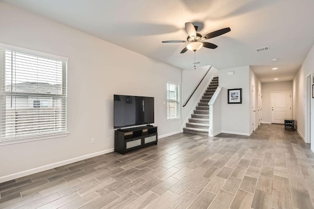 unfurnished living room featuring visible vents, stairs, baseboards, light wood-style floors, and a ceiling fan