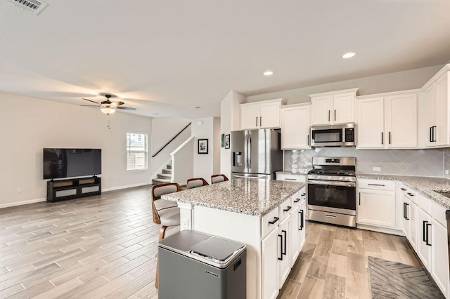 kitchen with light wood-style floors, appliances with stainless steel finishes, open floor plan, and visible vents