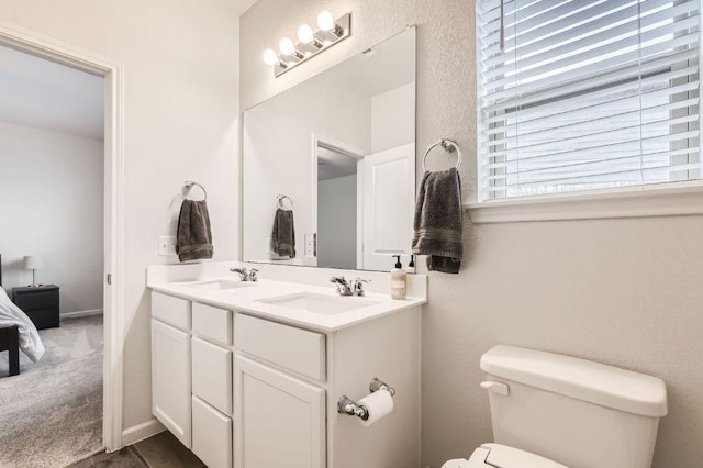 bathroom featuring double vanity, toilet, and a sink