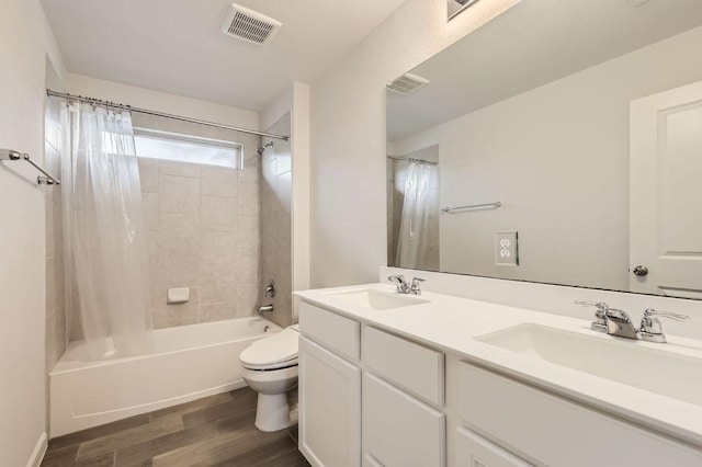 bathroom featuring visible vents, wood finished floors, a sink, toilet, and shower / bathtub combination with curtain