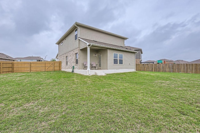 rear view of house with a lawn and a fenced backyard