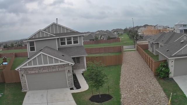 view of front of property featuring fence, concrete driveway, a front yard, and a residential view