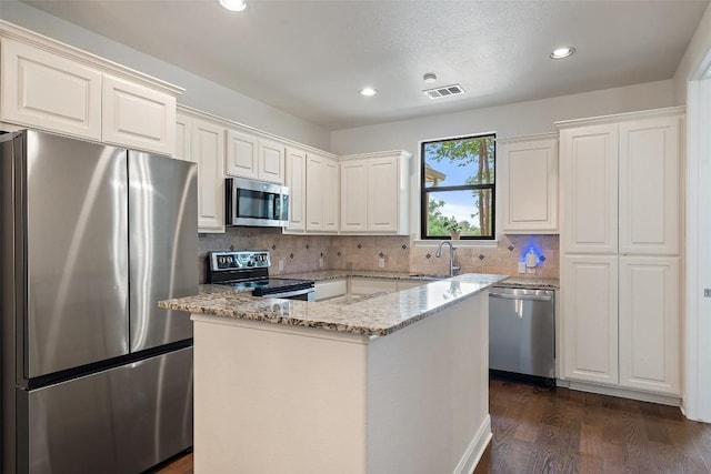 15105 Falcon Dr, Austin, TX 78734 - kitchen featuring stainless steel appliances, light stone counters, tasteful backsplash, dark wood-style floors, and a center island