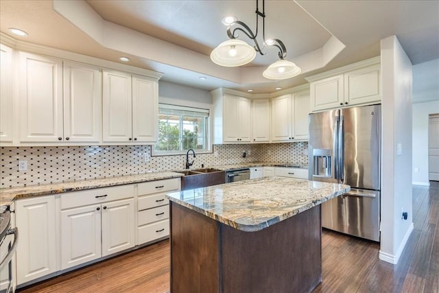 kitchen featuring a sink, a raised ceiling, white cabinets, and stainless steel appliances