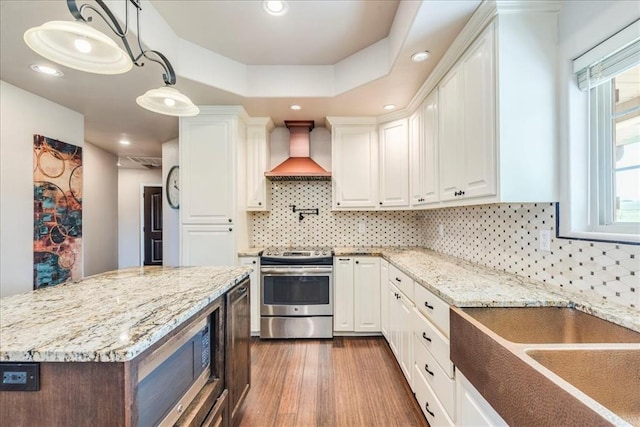 kitchen featuring light stone counters, white cabinets, custom exhaust hood, and stainless steel range with electric stovetop