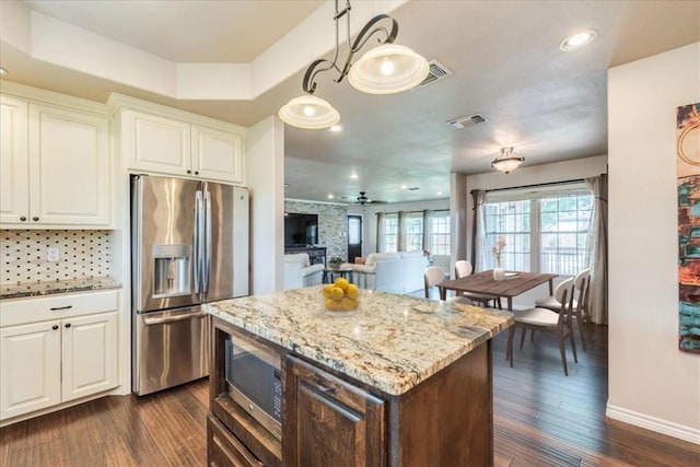 kitchen with visible vents, dark wood finished floors, light stone counters, baseboards, and stainless steel appliances
