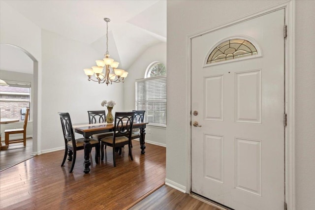 dining area with an inviting chandelier, arched walkways, wood finished floors, and a healthy amount of sunlight