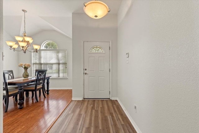entrance foyer with baseboards, a notable chandelier, light wood-style flooring, and vaulted ceiling