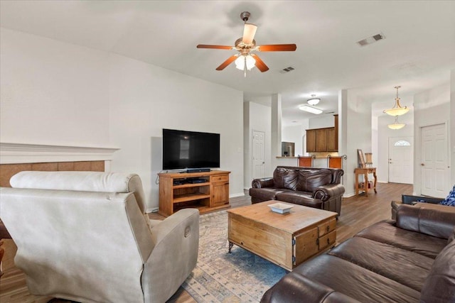 living area with visible vents, a ceiling fan, light wood finished floors, and baseboards