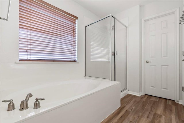 bathroom with a shower stall, a garden tub, and wood finished floors