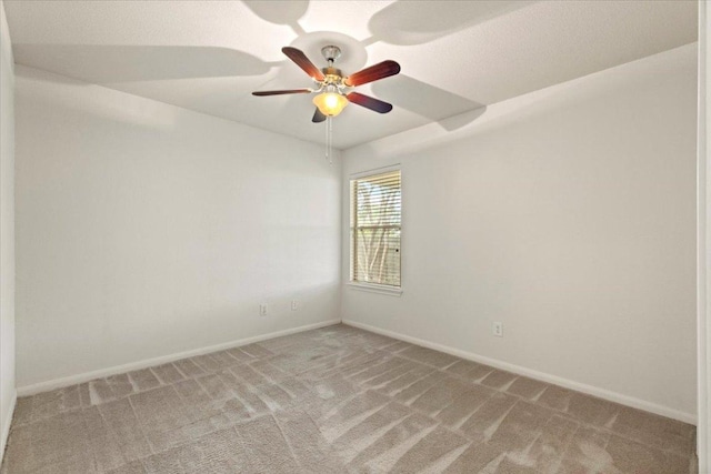 empty room with baseboards, ceiling fan, and light carpet