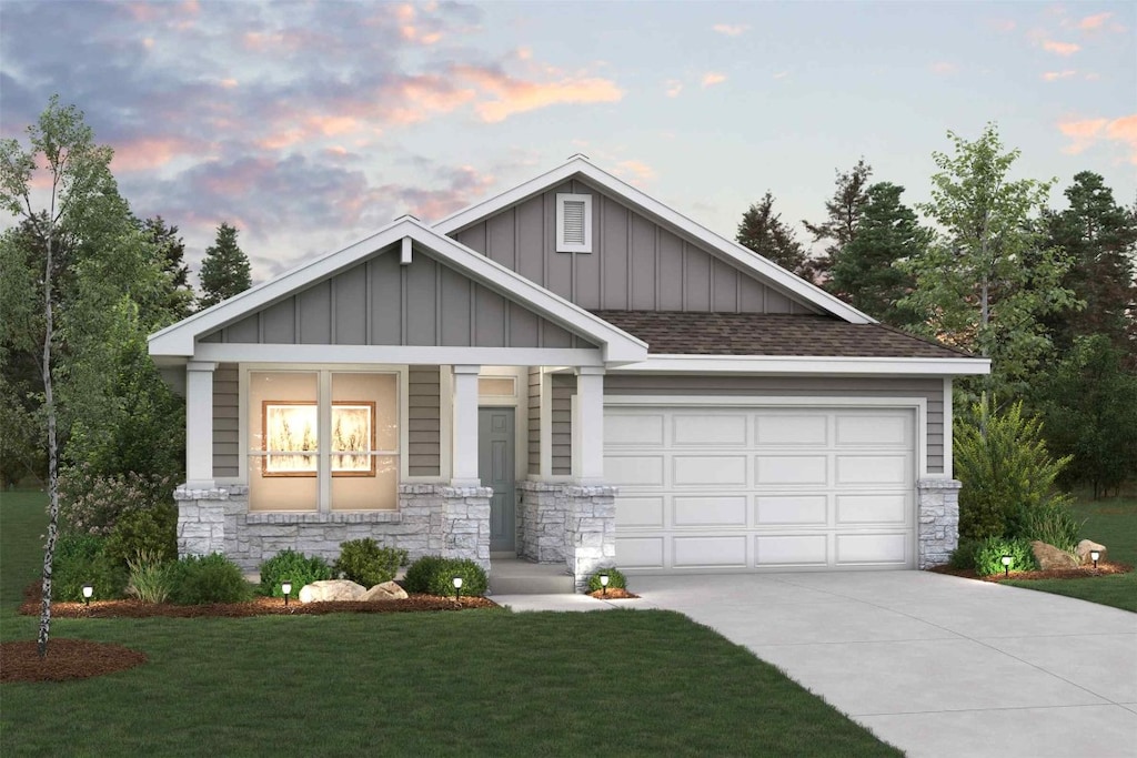 craftsman-style home featuring stone siding, a garage, board and batten siding, a front yard, and driveway