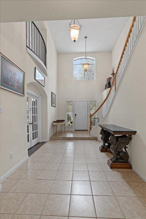 entrance foyer with a high ceiling, light tile patterned flooring, and stairway