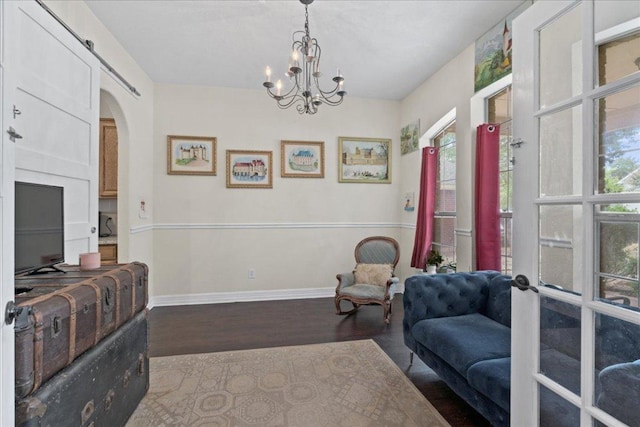 sitting room featuring baseboards, arched walkways, wood finished floors, and a wealth of natural light