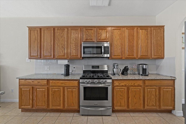 kitchen with brown cabinets, backsplash, and appliances with stainless steel finishes