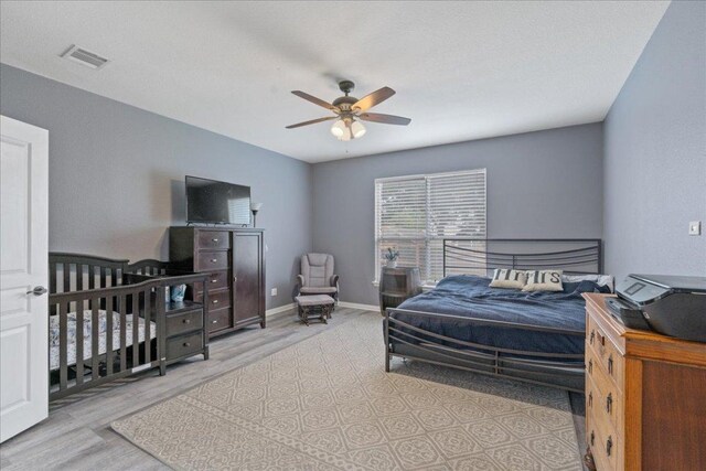 bedroom with a ceiling fan, baseboards, visible vents, and wood finished floors