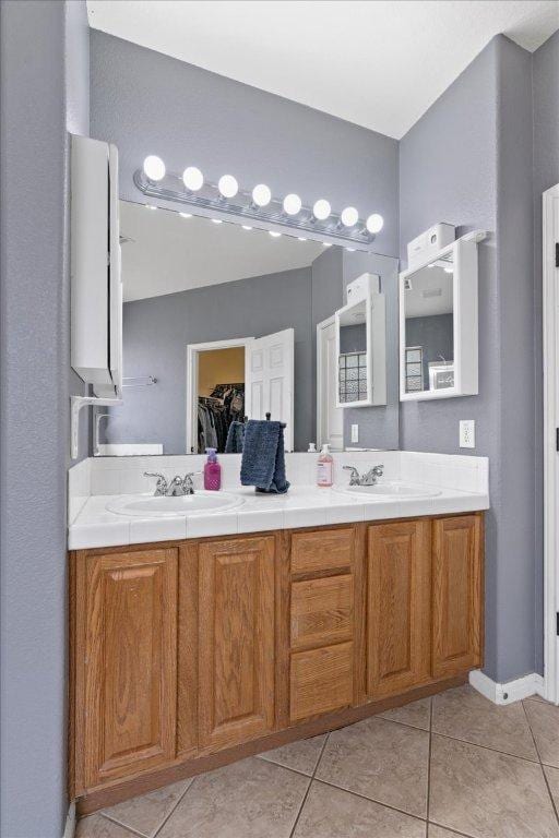 full bath with double vanity, a sink, and tile patterned flooring