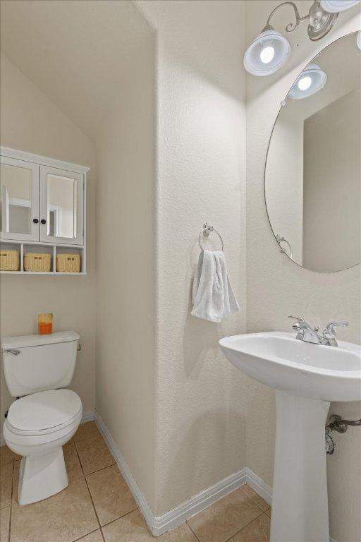 bathroom with toilet, tile patterned floors, a sink, and baseboards